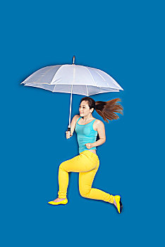蓝色背景上打伞的年轻女孩