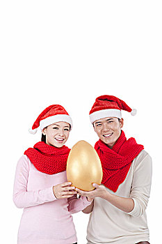 戴着圣诞帽的青年伴侣拿着金蛋