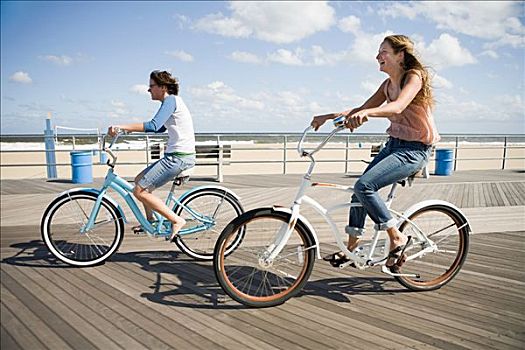 两个女人,骑自行车,木板路