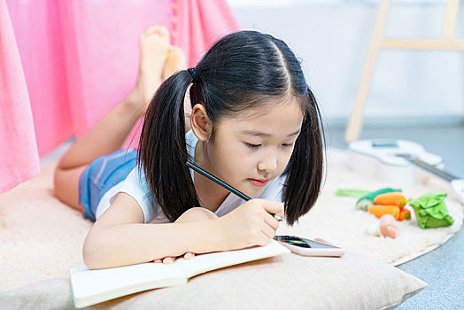 小女孩趴在地板上寫作業