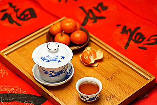 茶具和桔子放在春节红色对联福字背景上