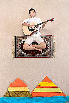坐在魔毯上弹吉他的男士