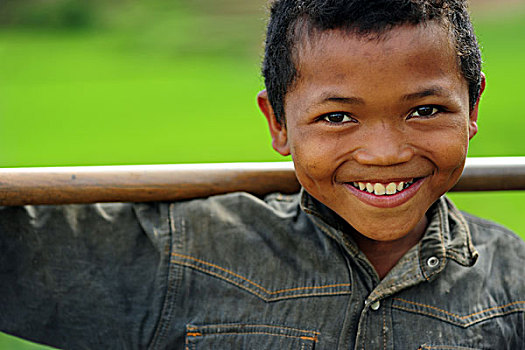 madagascar,ambalavao,portrait,of,young,boy,smiling,in,front,terraced,ricefield