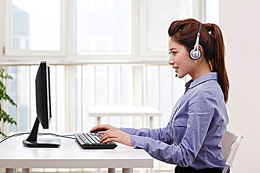 商务女士头戴耳机使用台式电脑