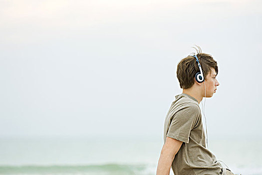 男孩,坐,海滩,听,耳机,侧面视角