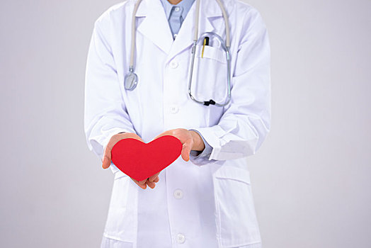一位戴口罩的年轻女医生拿着一颗红心