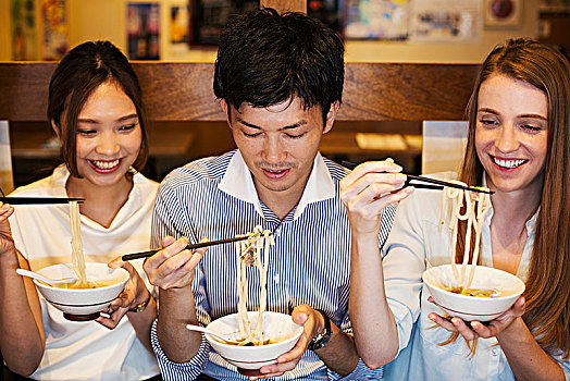 三个,微笑,人,坐,桌子,餐馆,吃,碗,筷子