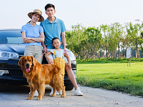 快乐的三口之家和宠物狗在轿车前合影