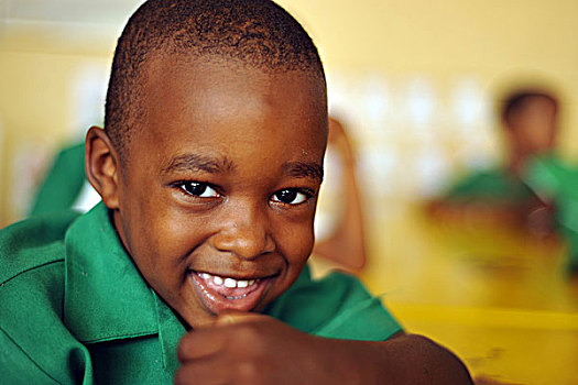 dominica,roseau,preschool,social,center,smiling,boy,at,yellow,school,table