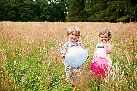 兄弟姐妹,高草,拿着,气球,看镜头,微笑