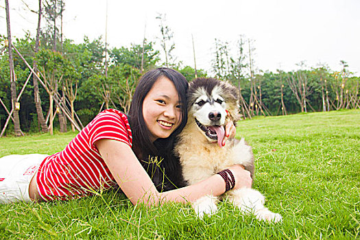 年轻的女孩和她的狗在草坪玩耍