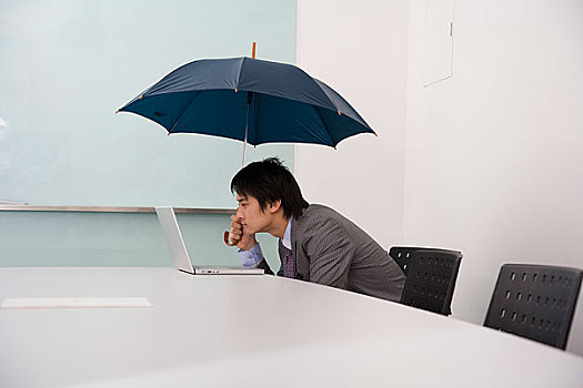 在会议室内打着伞工作的男员工