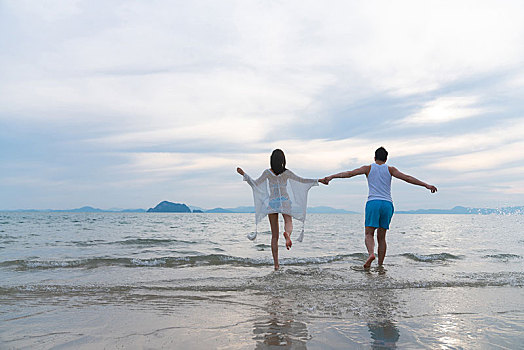 快乐的年轻情侣在海边玩耍