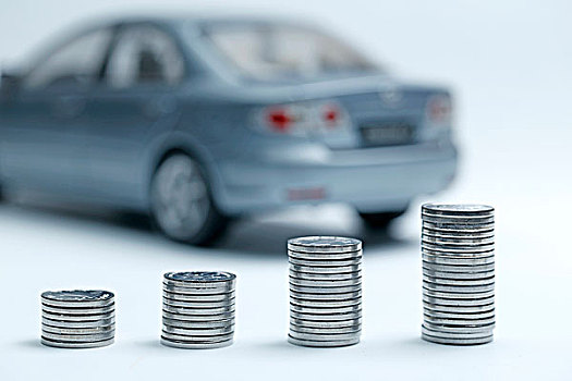 硬币堆放在汽车模型前,汽车贷款交易租赁销售概念