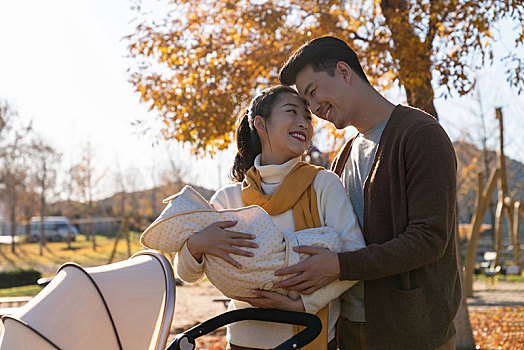 年轻夫妻推着婴儿车散步