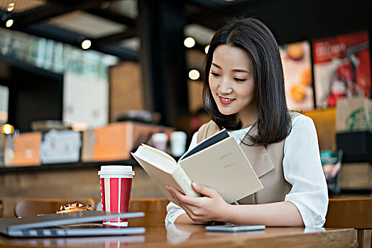 年轻女子在餐厅看书