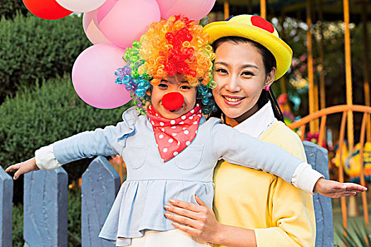小女孩扮小丑和年輕媽媽在游樂園
