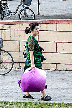 朝鲜街头肩背手提货物的百姓