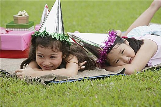两个女孩,戴着,派对帽,躺着,野餐毯,休息