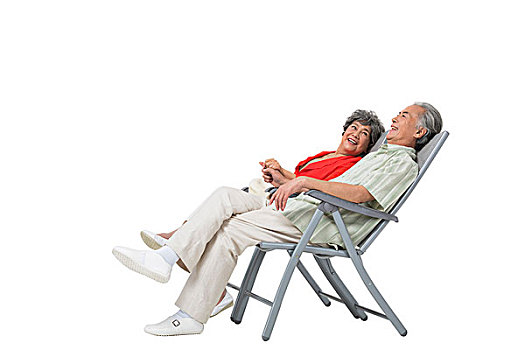 快乐的老年夫妇坐在沙滩椅上