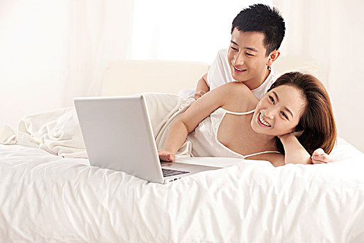 年轻情侣在床上用电脑