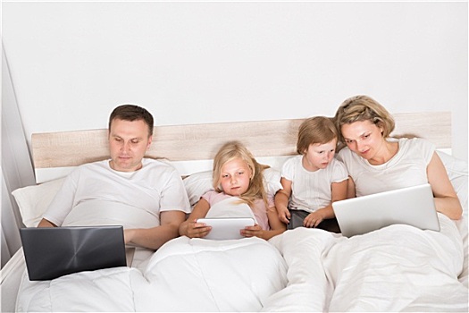 年轻家庭,笔记本电脑,床上