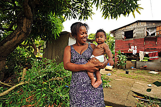 dominica,carib,territory,mother,holding,fat,baby,in,front,of,house