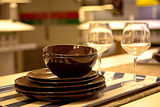 餐桌上放着咖啡色的盘子碗和红酒杯