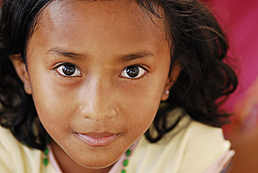 timorese,girl,sitting,on,the,ground,and,playing