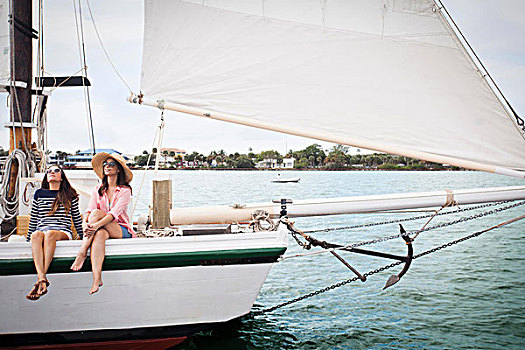 两个女人,坐,边缘,帆船,腿,悬着,上方