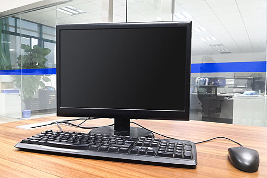 黑屏的台式电脑摆放在无人的办公室内办公桌上