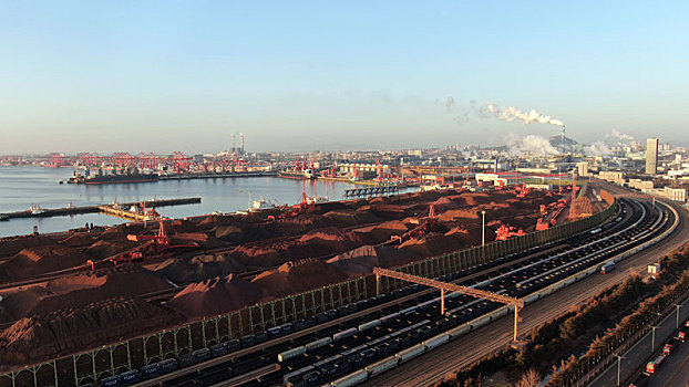 航拍港口生产作业现场,满载货物的火车从铁矿石堆场穿过