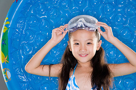 穿着泳衣戴着潜水镜的小女孩对着镜头微笑