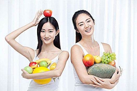 两个抱着水果的亚洲青年女性