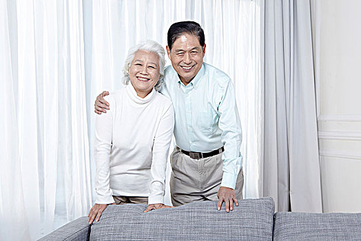 老年夫妇在沙发后微笑面对镜头
