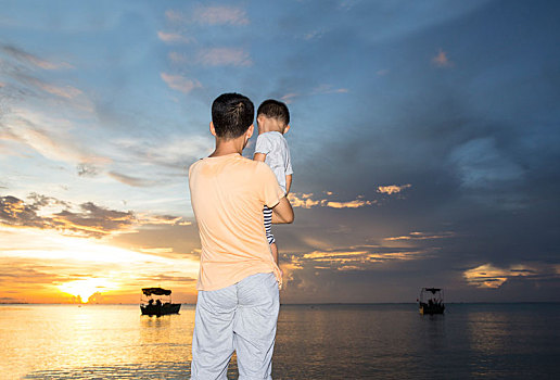 父亲抱起孩子看海