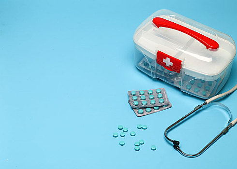 急救药箱和药片放在蓝色背景上