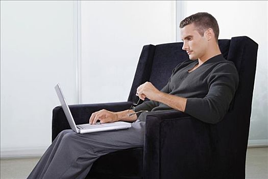 侧面,男青年,坐,扶手椅,工作,笔记本电脑