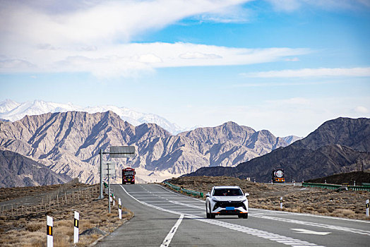 蓝天白云群山背景下的高速公路和行驶的汽车