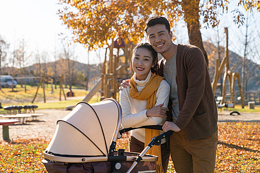 年轻夫妻推着婴儿车散步