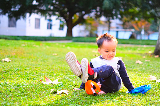 小男孩坐在电子科技大学沙河校区的草坪上看着小玩具