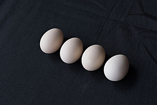 鸡蛋排列在黑色麻布背景上
