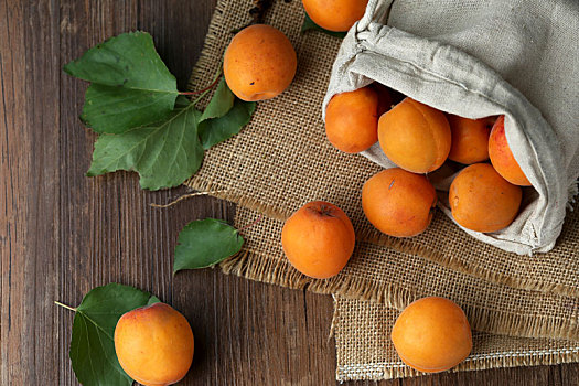 木桌上的杏放在粗麻布袋子里
