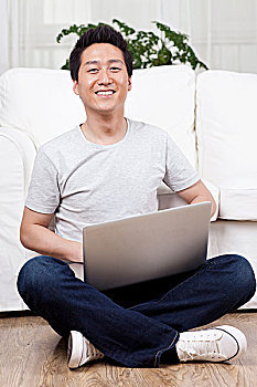 一个坐在地板上用笔记本电脑的青年男士