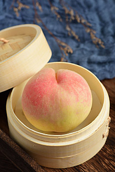 复古中国风格背景上放在蒸屉里的两个新鲜水果水蜜桃