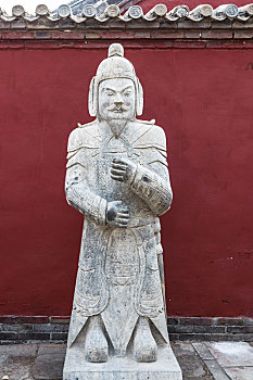 红色庙墙前面的古代武将雕塑