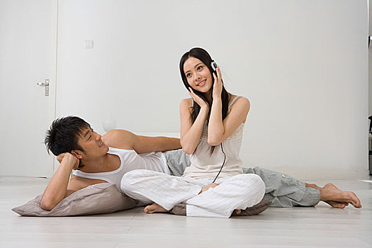 男人躺在地板上看坐在地板上听音乐的女人