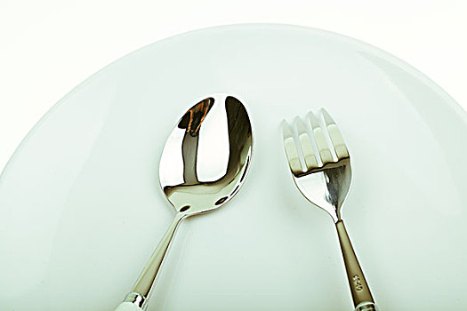白色盘子中放着银色叉子和勺子