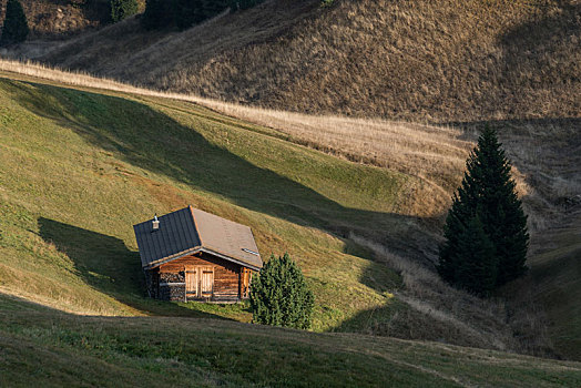意大利多洛米蒂山脉苏西高原秋季草原上的木屋和山地风景