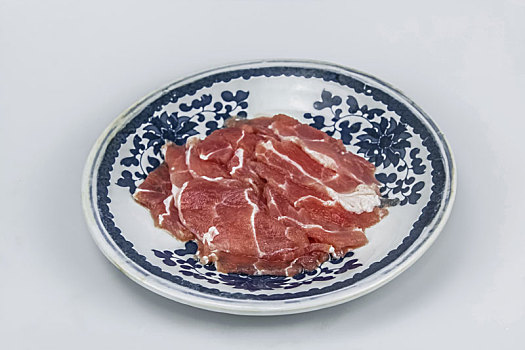青花瓷盘上新鲜猪肉片生食品